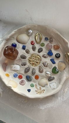 a white bowl filled with lots of different types of sea glass and seashells