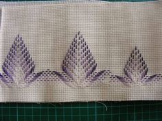 a close up of a piece of cloth with purple flowers on it and some thread