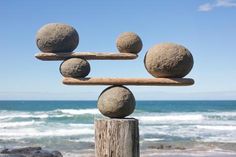 three stones balanced on top of each other in front of an ocean and sky background