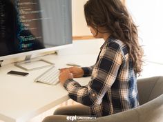 a woman sitting at a desk with a computer and keyboard in front of her on the screen