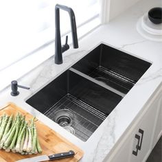 an image of a kitchen sink with asparagus on the cutting board next to it