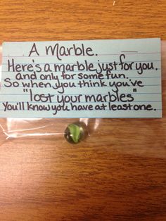 a note attached to a plastic bag on a wooden table with a green apple in it