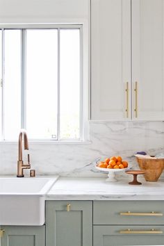 a kitchen with marble counter tops and white cabinets, along with brass pulls on the cabinet doors