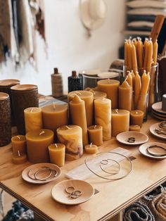 many candles are sitting on the table with plates and other items in front of them