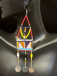 Kandake Drop & Dangle with Tassels Earrings.  These are highly decorated drop & dangle earrings, that end in delicate tassels.  The vibrant colors are matched only by the design of the earrings. In Maasai culture, a woman's status and position in society are reflected in the beadwork she wears, which in modern times is shown in detailed beadwork and color patterns.   The Maasai people chiefly inhabit the areas between Southern Kenya and Northern Tanzania. The colors in Maasai jewelry have meaning. Red symbolizes warriorhood and bravery. Blue is the color of water and white symbolizes peace. These beautiful earrings feature multiple colors. Approximately 5.5" in length and 1.5" in width. Made in Kenya. Great gift idea. To check out more of our earrings, click here: https://www.etsy.com/your Traditional Long Drop Beaded Earrings With Dangling Beads, Traditional Long Drop Beaded Earrings, Traditional Dangle Chandelier Earrings, Adjustable Multicolor Chandelier Earrings For Festival, Multicolor Long Drop Jewelry For Festivals, Traditional Adjustable Dangle Chandelier Earrings, Unique Multicolor Chandelier Earrings For Festival, Multicolor Single Beaded Earring For Festival, Multicolor Beaded Single Earring For Festival