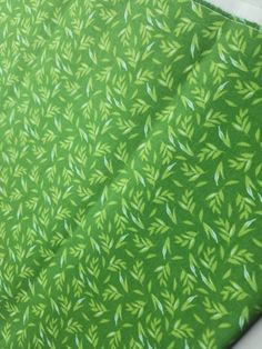 a green tie with leaves on it is laying on a tablecloth that has been folded over