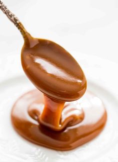 a spoon filled with melted chocolate on top of a white plate and covered in caramel sauce