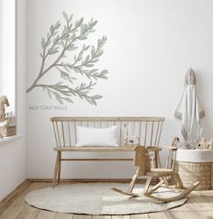 a baby's room with a rocking chair and tree wall decal