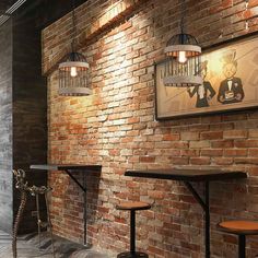 a brick wall with three stools in front of it and a painting on the wall