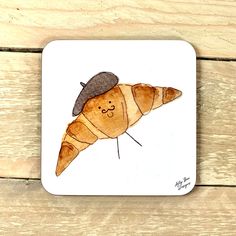 a coaster with a drawing of a croissant wearing a hat