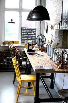 an industrial style kitchen with yellow chairs and wooden counter tops, black pendant light over the island