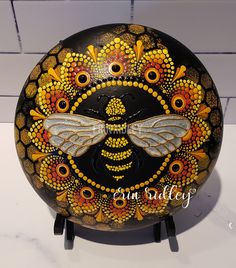 an artisticly painted round object with a bee on it's face and wings