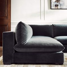 a black couch sitting on top of a wooden floor next to a painting above it