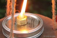 a lit candle sitting on top of a metal plate with rope hanging from it's sides