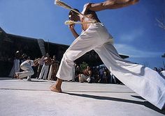 a man in white pants is doing tricks with a tennis racket