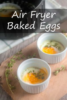 two white bowls filled with eggs on top of a wooden cutting board next to an air fryer