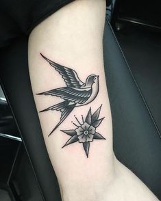 a small tattoo on the arm of a woman with a bird and flower in it