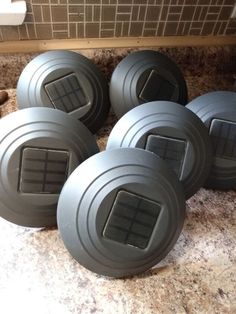 four gray round objects sitting on top of a counter next to a tile backsplash