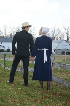 a man and woman standing next to each other near a fence