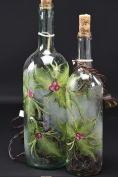 two glass bottles with green leaves and red berries on them