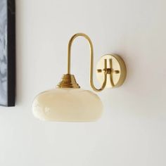 a light that is on the wall next to a painting and a lamp shade hanging from it's side