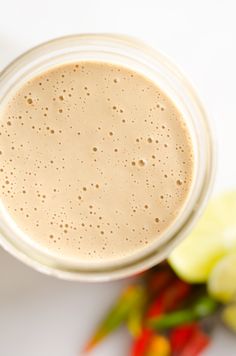 a glass filled with liquid sitting on top of a white table next to some vegetables