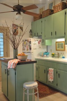 a kitchen with green cabinets and a ceiling fan