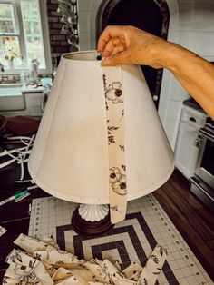 a person is holding a lamp shade with flowers on it and the fabric has been folded