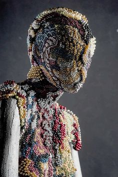 a beaded mannequin wearing a colorful shirt and tie with beads all over it