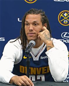 a man with dreadlocks sitting in front of a microphone and talking on the phone