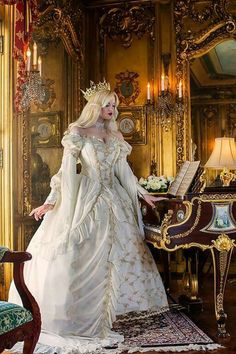 a woman in a white dress standing next to a piano and ornately decorated wall