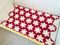 a crocheted red and white blanket with snowflakes