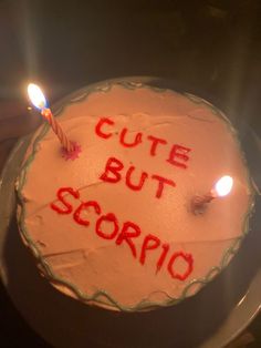 a white cake with red writing on it and two lit candles in front of it