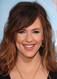 a close up of a person wearing a necklace and smiling at the camera with her hand on her hip