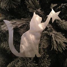 a metal cat ornament hanging from a christmas tree