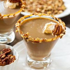 two desserts with pecans and whipped cream in them on a white tablecloth