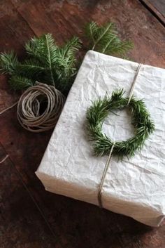 a present wrapped in white paper and tied with twine, surrounded by greenery