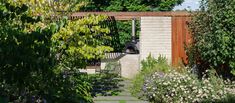 an outdoor patio and garden area in the middle of a wooded area with trees, shrubs, and flowers