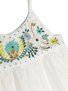 a white dress with blue and yellow flowers on the front, hanging from a hanger