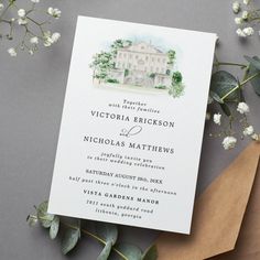 the wedding card is laying on top of some flowers and paper with greenery around it