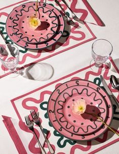 two pink plates and silverware on a table