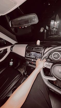 a person driving a car with their hand on the steering wheel