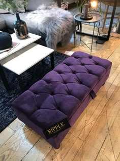 a purple bench sitting in the middle of a living room next to a coffee table