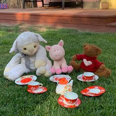 stuffed animals and teacups sitting in the grass