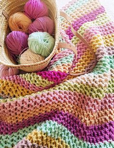 a basket filled with balls of yarn sitting on top of a blanket