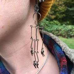 a close up of a person wearing some kind of earring on their neck with trees in the background