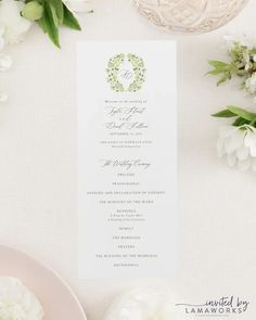 the wedding program is displayed on a table with white flowers and greenery around it