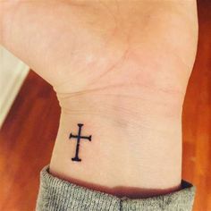 a small wrist tattoo with a cross on the inside of it's left arm