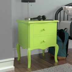 a bright green nightstand next to a bed with shoes on the floor and a black lamp