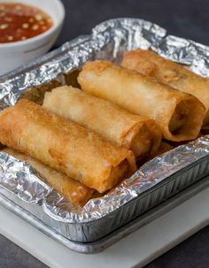 some food is sitting on top of tin foil and next to a bowl of dipping sauce